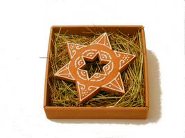 Piernikowa gwiazda z dziurką w kształcie gwiazdki, w pudełku na sianku.